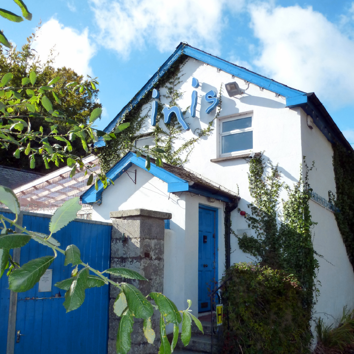 White building with blue 'inis' sign, surrounded by greenery