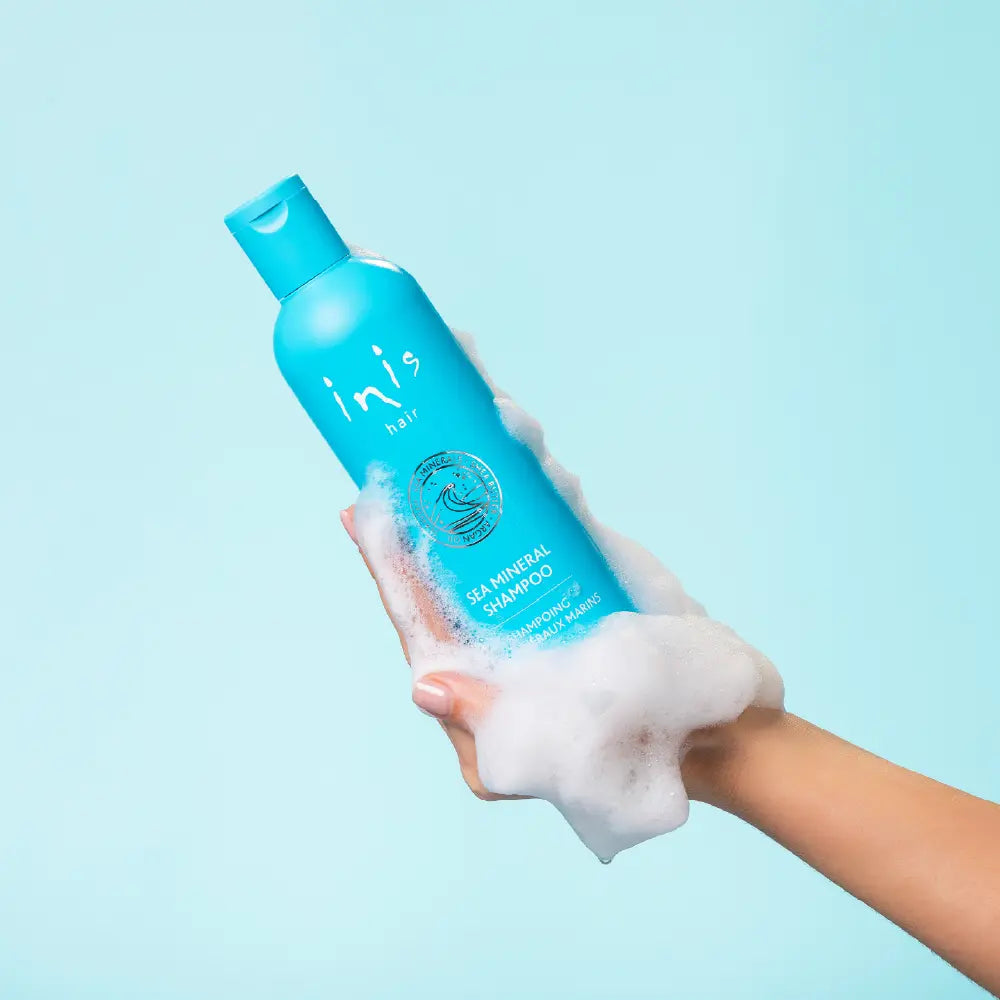 Blue shampoo bottle with 'inis hair' branding on a white background